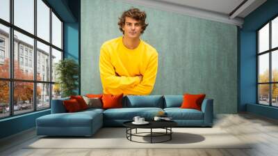 male fashion model in yellow sweater against green background Wall mural