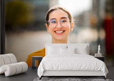 Portrait of attractive young caucasian woman smiling outside Wall mural