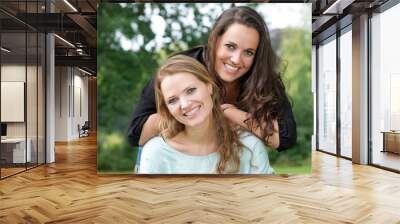 Portrait of two adult sister smiling together outdoors Wall mural