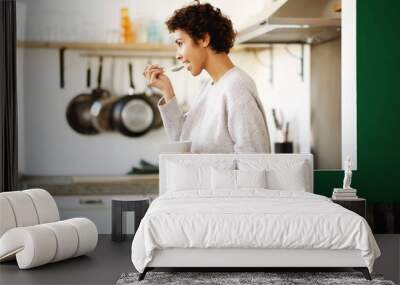 Profile of happy young woman eating cereal at home kitchen Wall mural