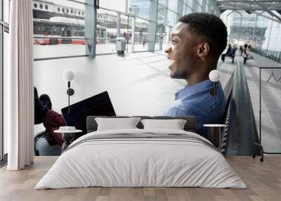 Side of african american businessman waiting at station with laptop Wall mural