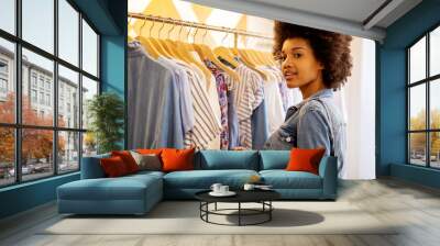 Side of beautiful young african woman shopping for clothes in store Wall mural