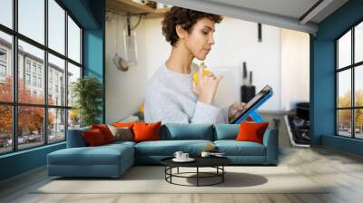 side portrait of young woman in kitchen looking at digital tablet Wall mural