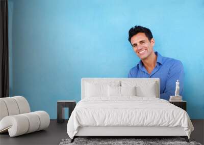 smiling businessman leaning against blue wall Wall mural