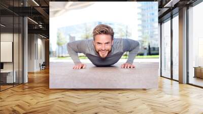 Smiling man doing push ups outdoors in the city Wall mural