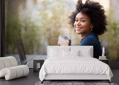 smiling young african american business woman sitting with laptop and cup of coffee Wall mural