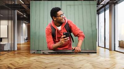 smiling young african american man with glasses and cellphone Wall mural