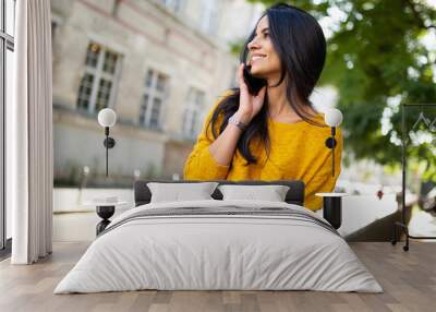 smiling young latin woman talking with cellphone in city Wall mural