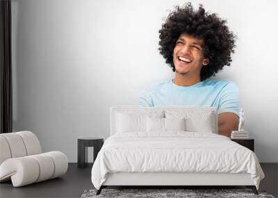 smiling young man with afro hair and arms crossed smiling by white background Wall mural