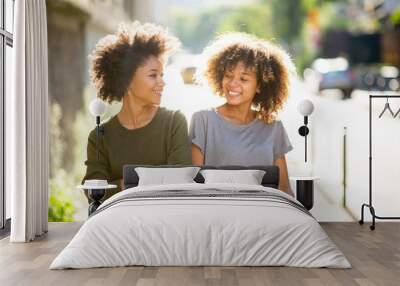 two black female friends walking and smiling in city Wall mural