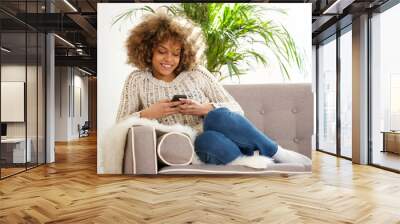 young african woman relaxing at home and using mobile phone Wall mural