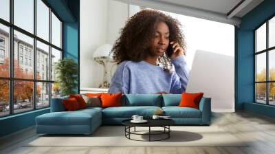 young black woman talking on mobile phone and using laptop Wall mural