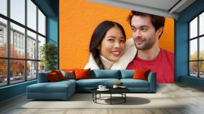 Young man and woman posing against orange background Wall mural