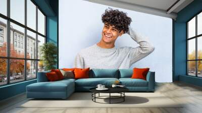 young man laughing with hand in hair by blue wall Wall mural