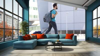 Young man walking outdoors with suitcase Wall mural