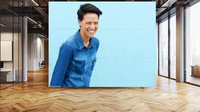 young woman laughing against blue background Wall mural