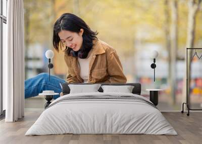 young woman sitting outside writing in book Wall mural