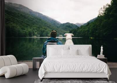 Man sitting with a dog on dock at the lake Wall mural