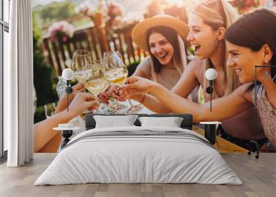 Young female friends clinking glasses with wine on the summer terrace of cafe or restaurant Wall mural