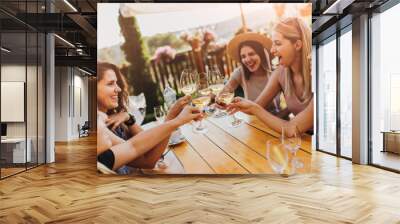 Young female friends clinking glasses with wine on the summer terrace of cafe or restaurant Wall mural