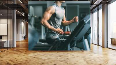 young man in sportswear running on treadmill at gym Wall mural