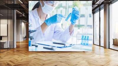 Medical or scientific researcher or man doctor looking at a test tube of clear solution in a laboratory Wall mural