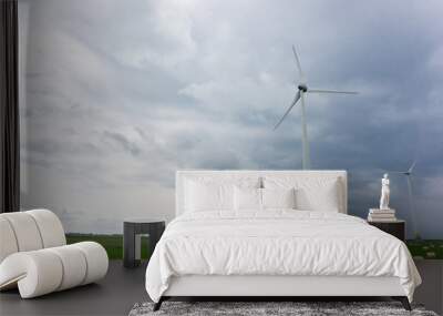 Wind Turbines and green fields with hay rolls on a cloudy day. Near storm Wall mural