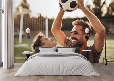 Father and son having fun together playing with a soccer ball on a sunny day in a suburban environment Wall mural