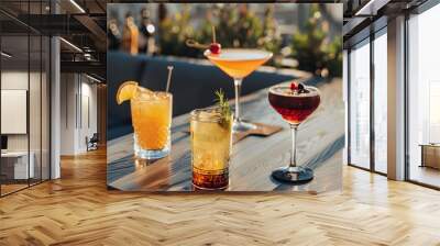 Four refreshing cocktails sitting on a wooden table of a rooftop bar at sunset Wall mural