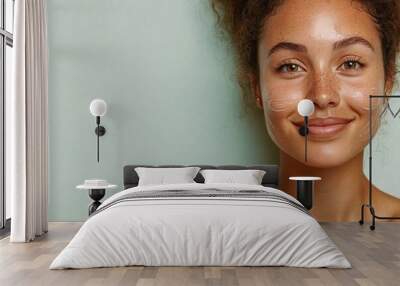 Beautiful smiling woman applying moisturizer cream on face Wall mural