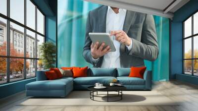 Businessman using his digital tablet near a glass wall Wall mural