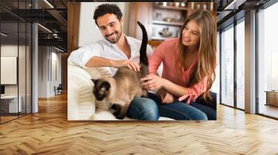 happy couple playing with their siamese cat Wall mural