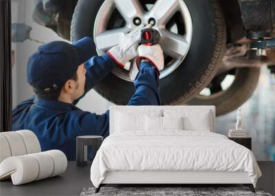 Mechanician changing car wheel in auto repair shop Wall mural