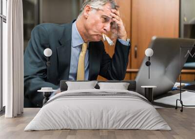 Nervous businessman smoking a lot of cigarettes at once while looking at his computer Wall mural