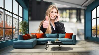 Smiling business woman talking on the phone and thumbs up Wall mural