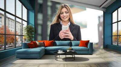 Smiling business woman using her mobile phone Wall mural