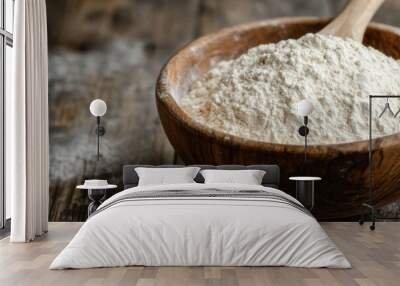 Wooden spoon resting in a bowl of white flour on rustic wooden table Wall mural