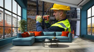 A construction working working in a building site carrying a metal bar on his shoulder. Wall mural