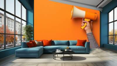 Orange Megaphone Held by Hand on Orange Background Wall mural