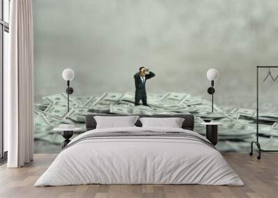 Miniature people figure toys photography. Inflation and recession concept. Businessmen standing above dollar money pile using binoculars searching for solution Wall mural