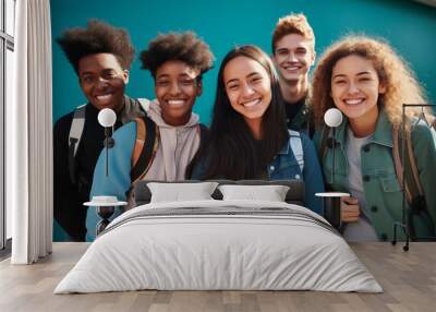 A happy group of teenage friends with backpacks smiling together against a vibrant blue wall Wall mural