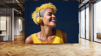 A smiling woman with bright yellow headphones and matching hair, enjoying music outdoors on a sunny day. Wall mural