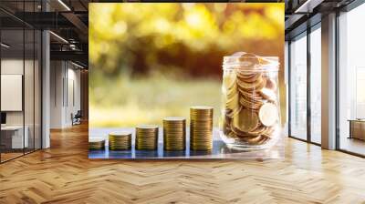 Coins in glass jar  Set on wooden plate, put in a  nature background also some coins beside. Wall mural