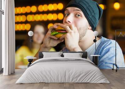 man in hands holds a burger. Man holding a burger and smiling Wall mural