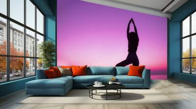 Silhouette of woman practice yoga on beach of sunset background Wall mural