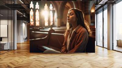 a young woman praying in church. Conceptual image for Christian faith, religion and prayer. Wall mural