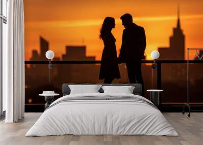 The silhouette of a couple in love. A man and woman stand on a rooftop terrace in front of a sunset and skyline. Wall mural