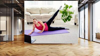 Beautiful young woman doing working out exercise on floor at home, online training on laptop computer, copy space. Yoga, pilates exercising. Sport, healthy lifestyle concept Wall mural