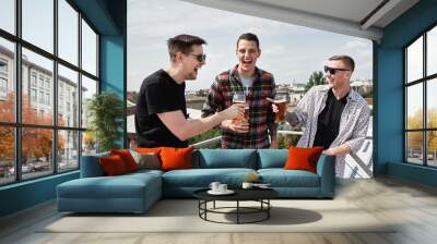 Happy smiling male friends drinking beer at bar or pub on roof, copy space. Friendship and celebration concept Wall mural