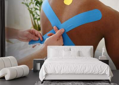 Physical therapist applying tape to patient back, copy space, closeup. Kinesiotaping. African man Wall mural